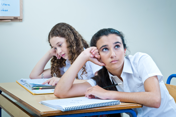 a photo of a girl sitting at a desk in class, she seems to be daydreaming