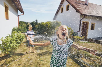 kids running through a water hose spray