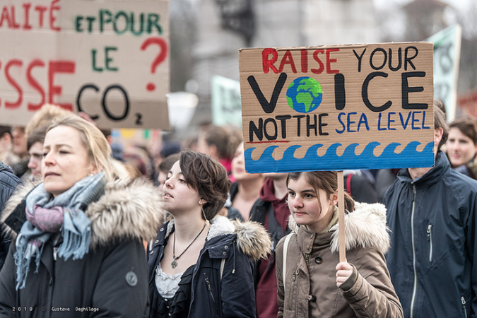 students at a climate strike in Lausanne, Switzerland, a girl carries a sign that reads "Raise your voice, not the sea level"