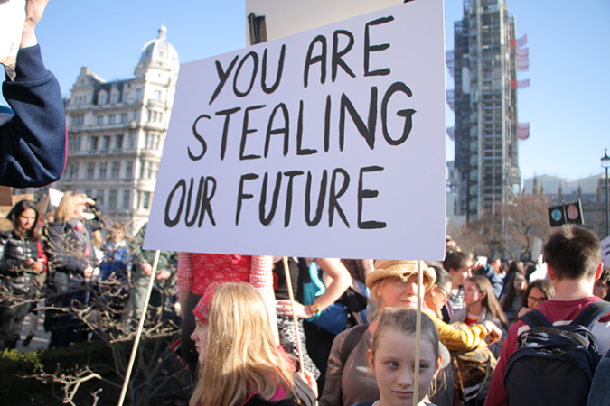 a student carrying a sign that reads "You are stealing our future" at a climate strike in London