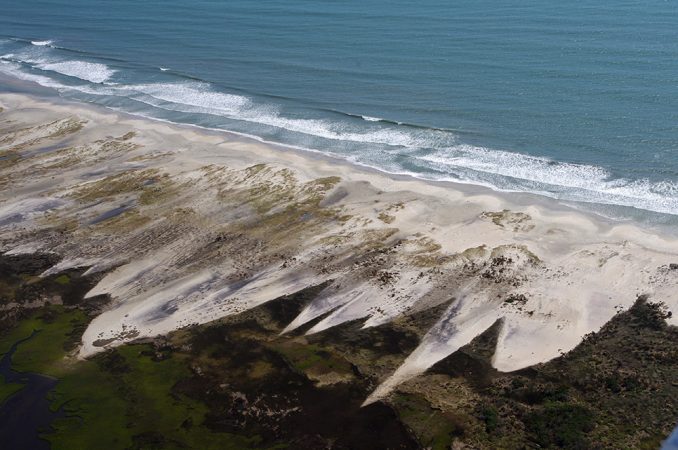 In 2011, Hurricane Irene’s winds and surf eroded the beach at Cape Lookout, N.C. The storm threw beach sand back onto the central part of the island. Eventually, such storm damage can remove the beach facing the open ocean. Over time, this will help to roll the entire island backward, bringing it closer to the mainland. Credit: Nat’l Park Serv.