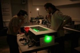 a photo of two scientists shooting a laser into a cloud chamber