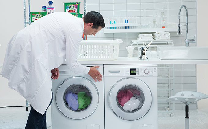 A man in a lab coat bending over to do laundry