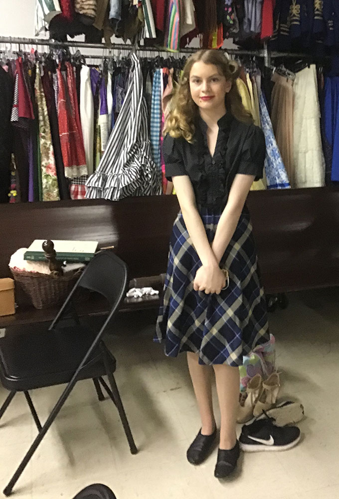 Beatrice Barilla posing in her costume in front of costume racks.