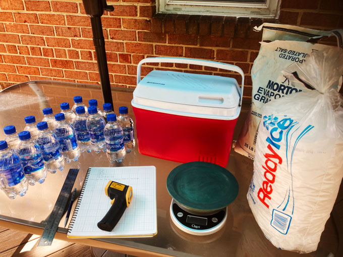 a photo of a cooler, some water bottles, salt, ruler, plate and notebook on a table ready for the experiment