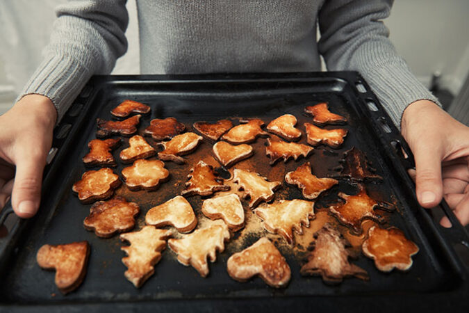 a photo of hands holding a tray of badly burned cookies