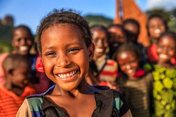 a photo of Ethiopian kids smiling at the camera in bright sunshine