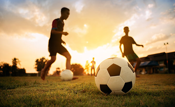 a photo of kids playing soccer at dusk