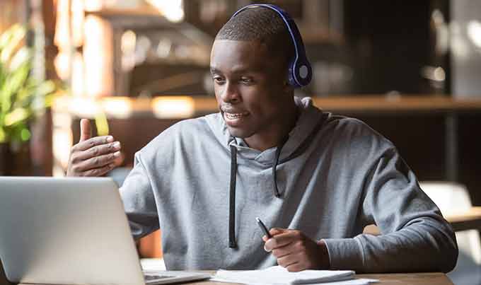 a young Black man wearing headphones mentoring over video chat