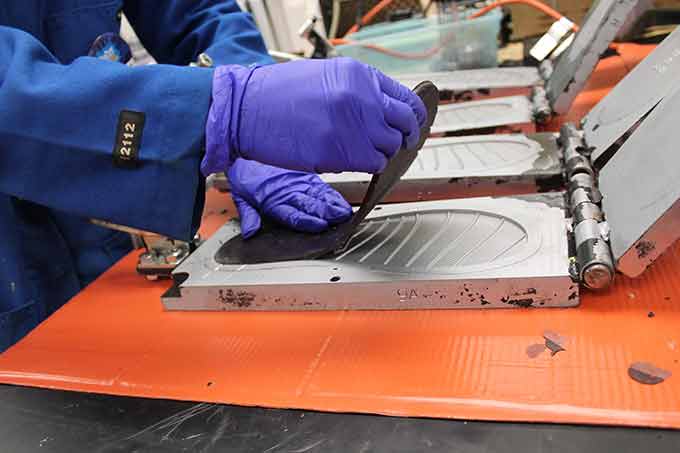 A researcher removes the sole of a new flip-flop from a mold.