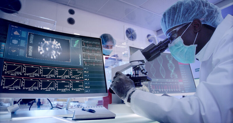 a Black researcher looks through a microscope in a lab