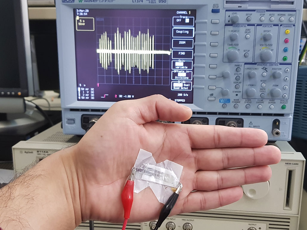 an open hand in front of a machine, there is a white mat with wires hanging out of it on the hand