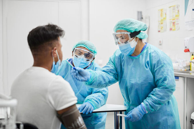 Two health care workers testing a patient for COVID. 