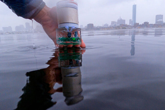 a close up of a hand placing a sensor into calm ocean water