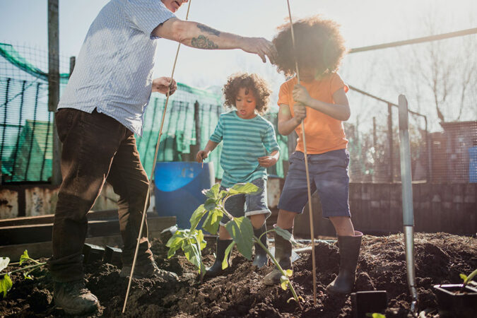 a photo of some kids gardening with a grandparent