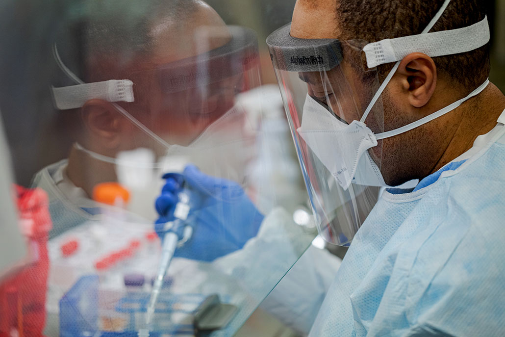 a photo of a microbiologist extracting COVID-19 from a sample