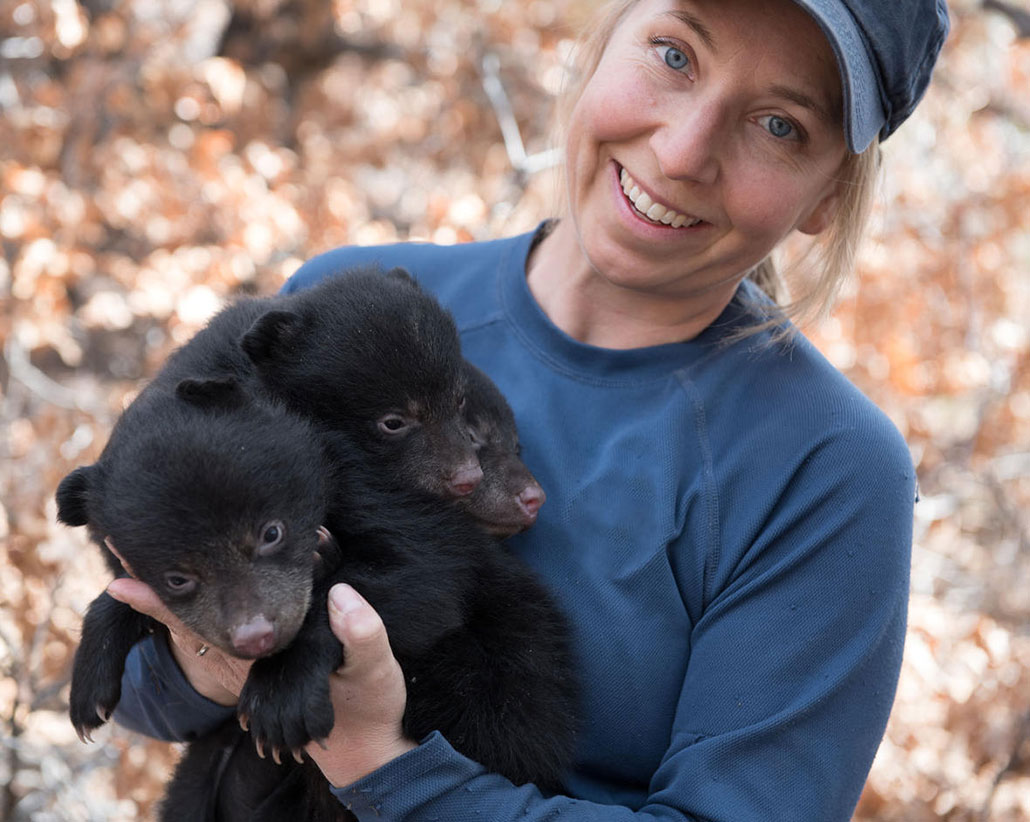 Heather Johnson holds two baby black bears and smiles