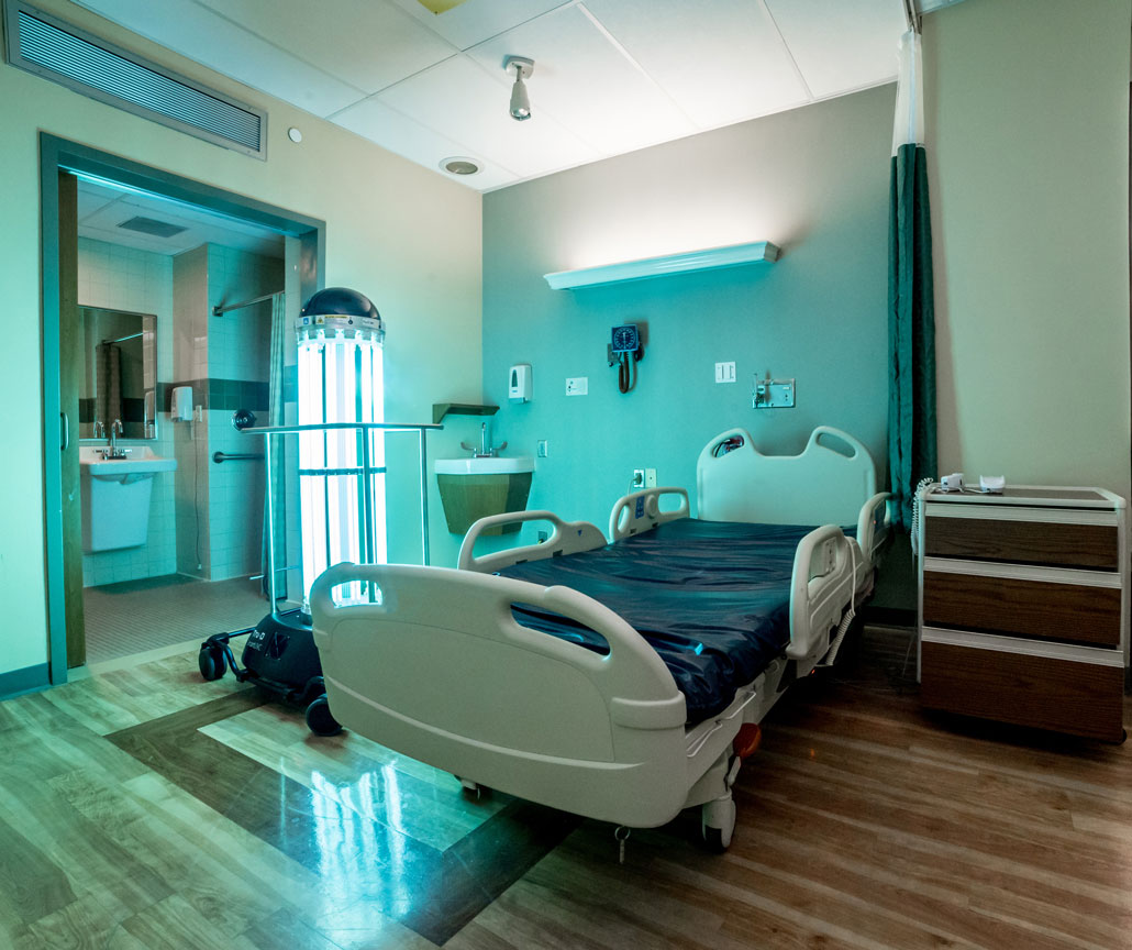a photo of a hospital room and the Tru-D Smart UVC robot - a pillar of UV lights on wheels