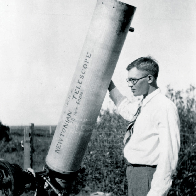 Clyde Tombaugh standing outside next to his telescope