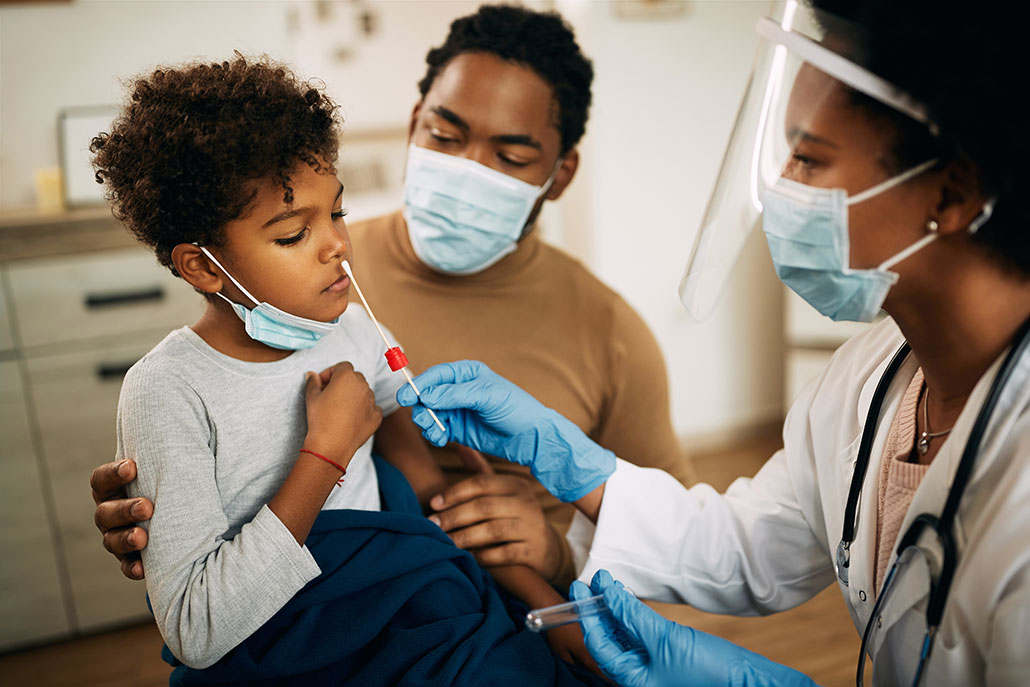 a young brown boy at the doctor about to get a COVID test swab - his father is holding him