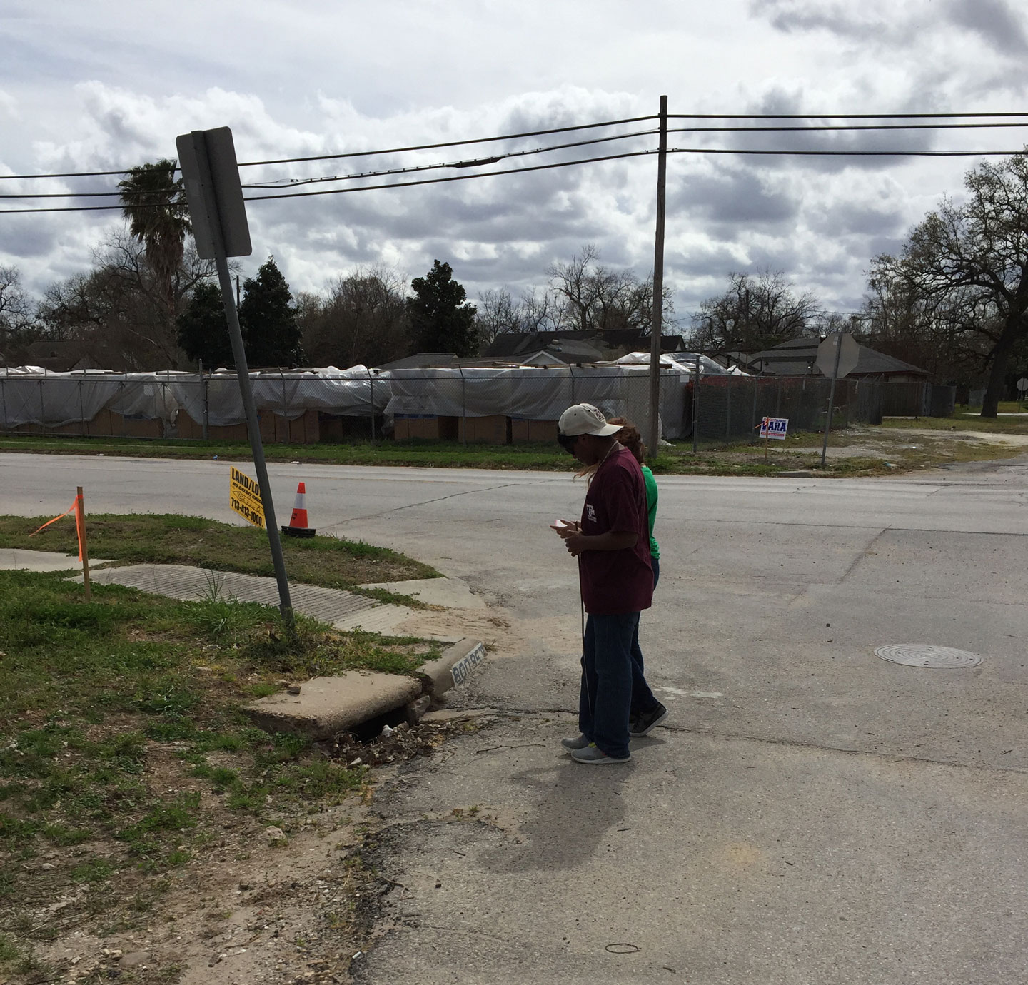 two high school students look at a storm drain