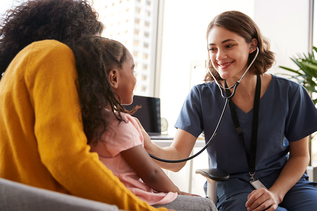 a doctor holds a stethoscope up to a young female patient