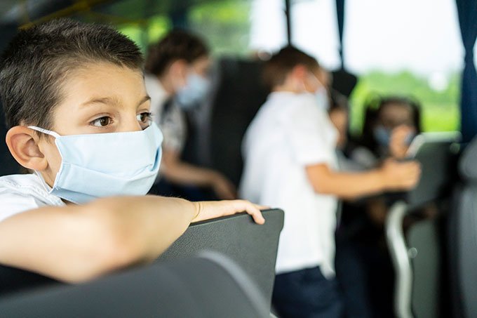 kids on a school bus wearing face masks
