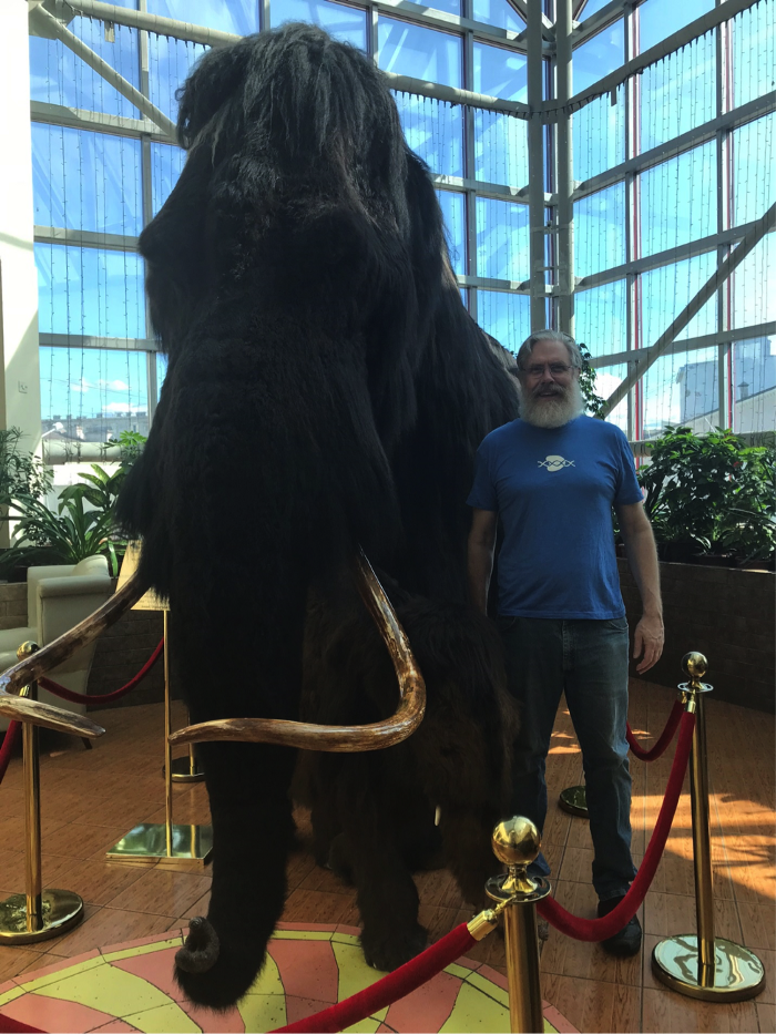 George Church poses with a woolly mammoth in a hotel lobby