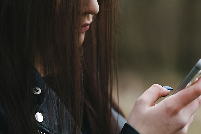 an image of a girl looking at her phone from the side, her hair covers her face