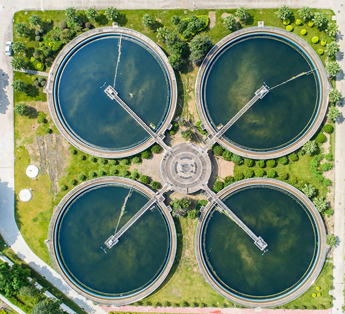 an aerial view of a sewage treatment plant, looking down on four circular bodies of water