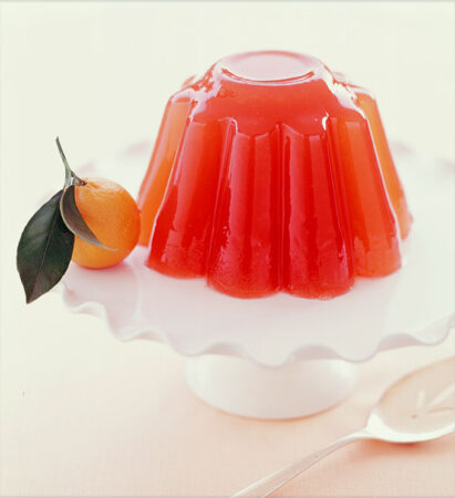 a photo of a molded red-orange desert jello on a stand