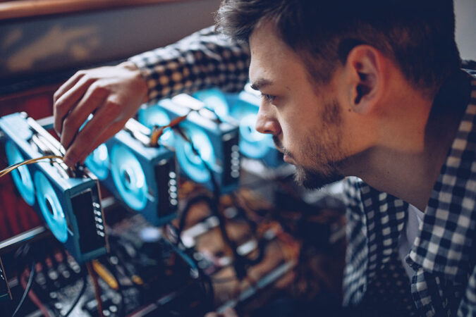a picture of a guy adjusting one of the GPUs on a mining rack