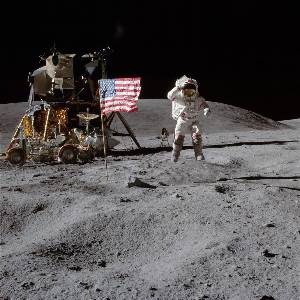 A photo of astronaut John Young bouncing across the moon. The photo shows him mid-bounce, suspended in the air.