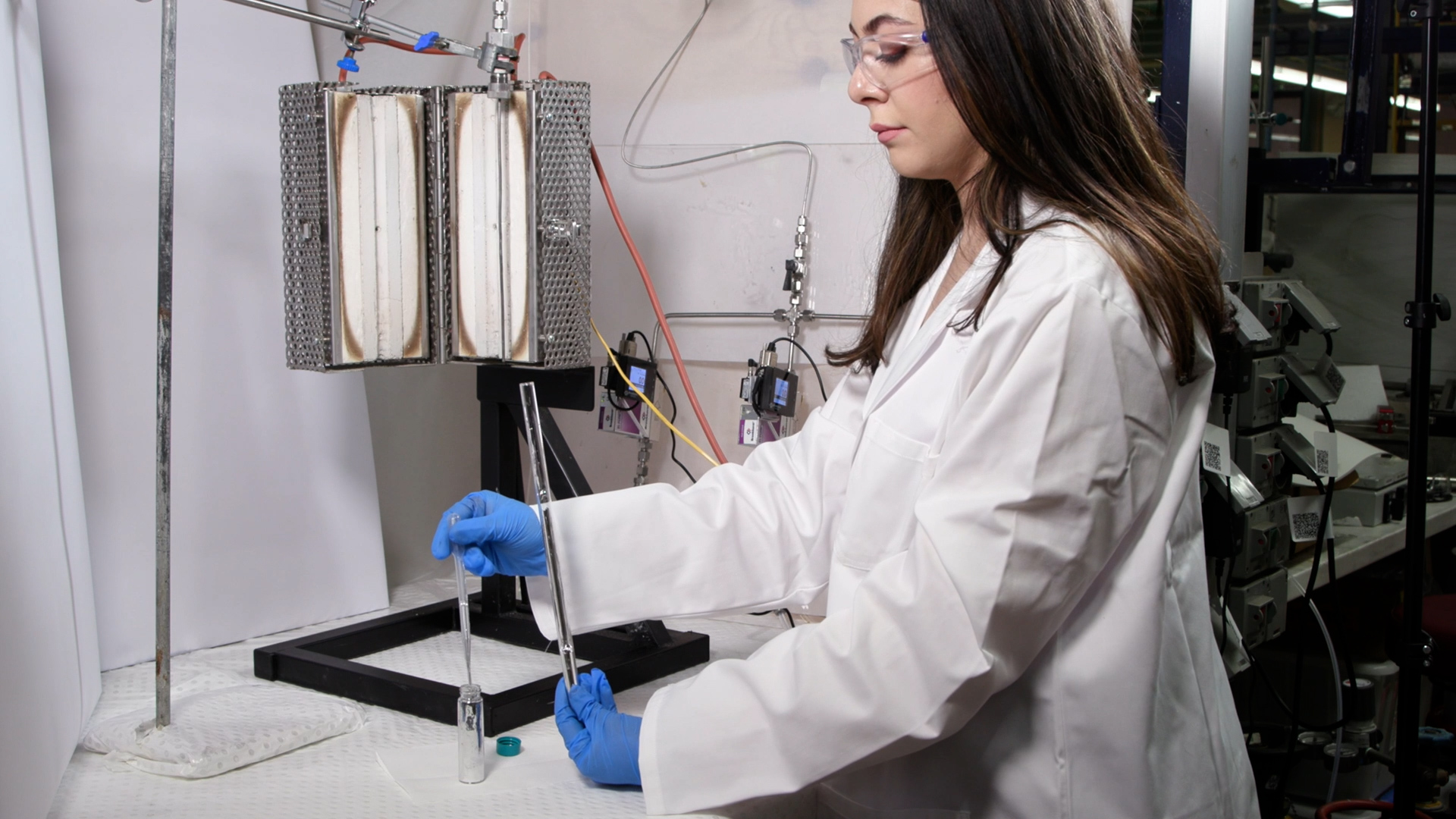 a woman in a lab coat and goggles works in a lab