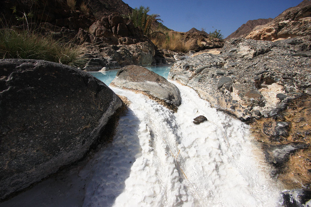 a photo of a white waterfall overflowing from a blue spring