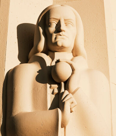 a statue with the likeness of Isaac Newton carved into a tan rock