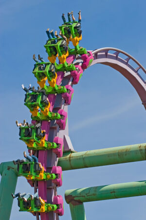 a photo of a roller coaster full of people approaching an upside down loop