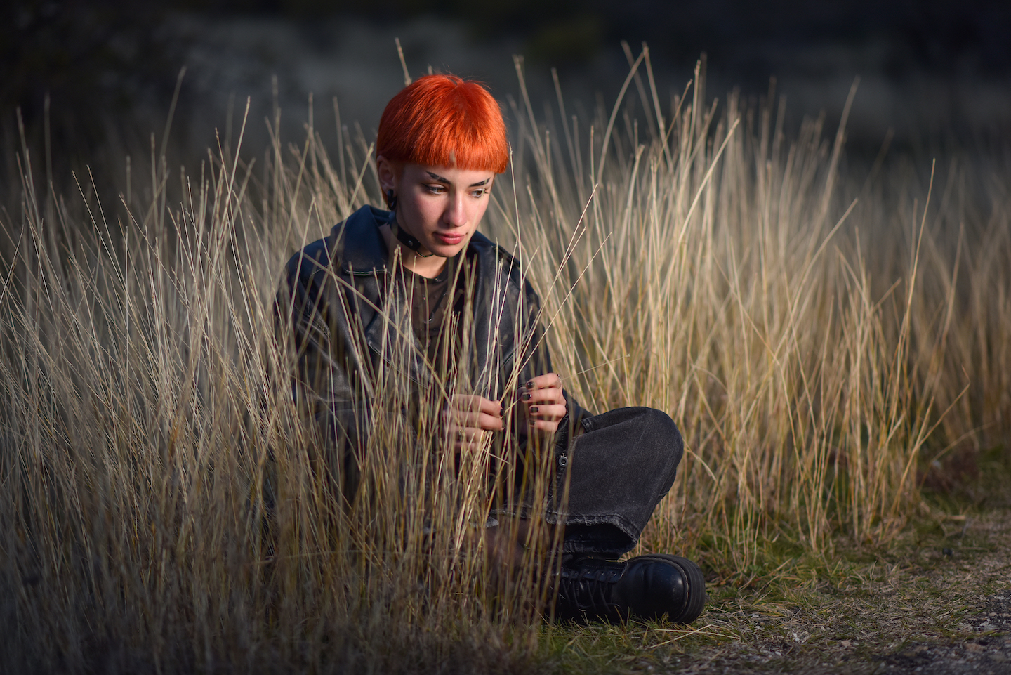 a girl with short red hair sits solemnly on the ground