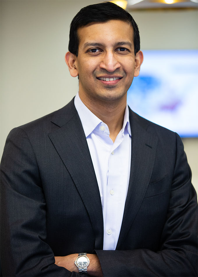 A man wearing a black suit smiles at the camera