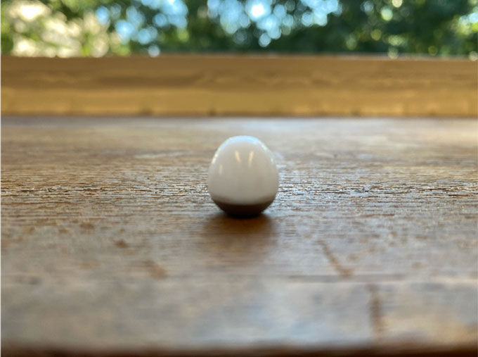 a phto of a white egg-like object on a wood table