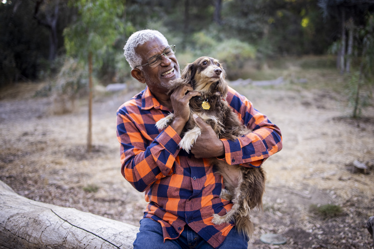 A senior black man with a cute long haired dachshund outdoors