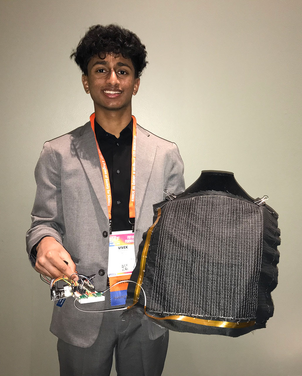 una foto de Vivek Sandrapaty sosteniendo un prototipo de chaleco antibalas